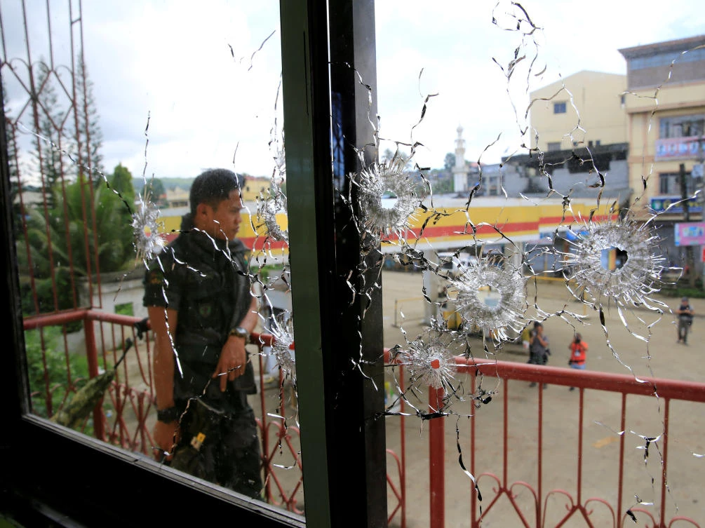 FILE PHOTO: A policeman stands on guard behind a window full of bullet holes as government soldiers assault the Maute group in Marawi City, Philippines May 31, 2017. (REUTERS)