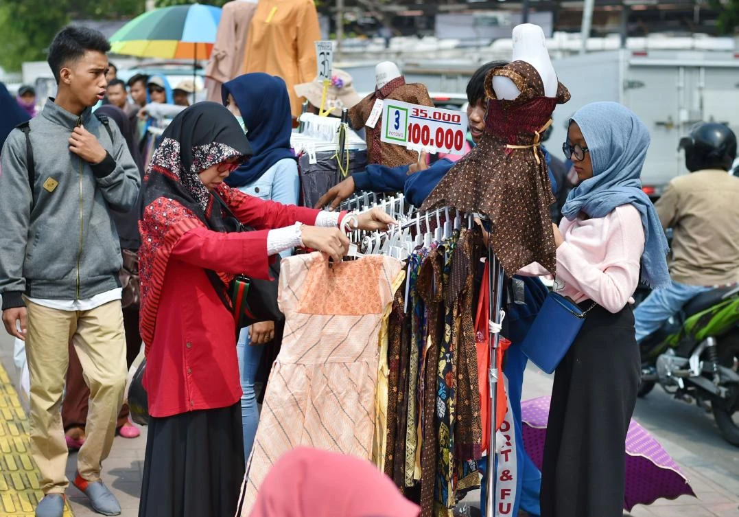 Indonesian bargain for reasonable price clothes at a sidewalk stall in Jakarta on June 9, 2017. The global economy is set to post solid growth this year, amid improving world trade and better performance by large emerging markets, but key risks could still threaten the outlook, the World Bank said, where the seven largest emerging market economies -- China, Brazil, Mexico, India, Indonesia, Turkey and Russia -- remain the key engine for the world economy, they added. (AFP)