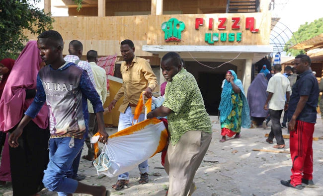 Men carry a body at the scene of an attack outside a hotel and an adjacent restaurant in Mogadishu, Somalia, on Thursday. (REUTERS)