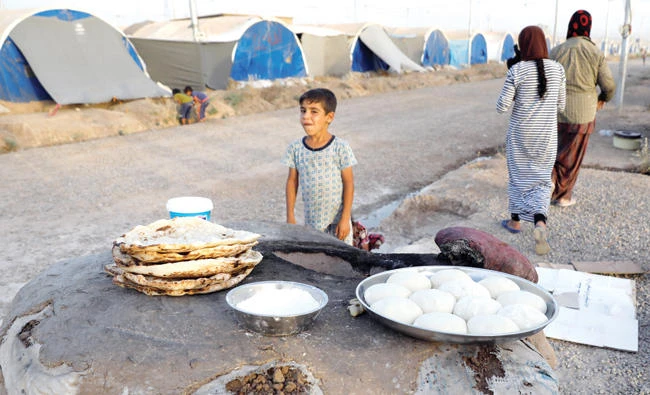Displaced Iraqi family from Mosul bake bread for their Iftar, during the Muslim holy month of Ramadan at a refugee camp Al-Khazir in the outskirts of Erbil, on Saturday. (Reuters)