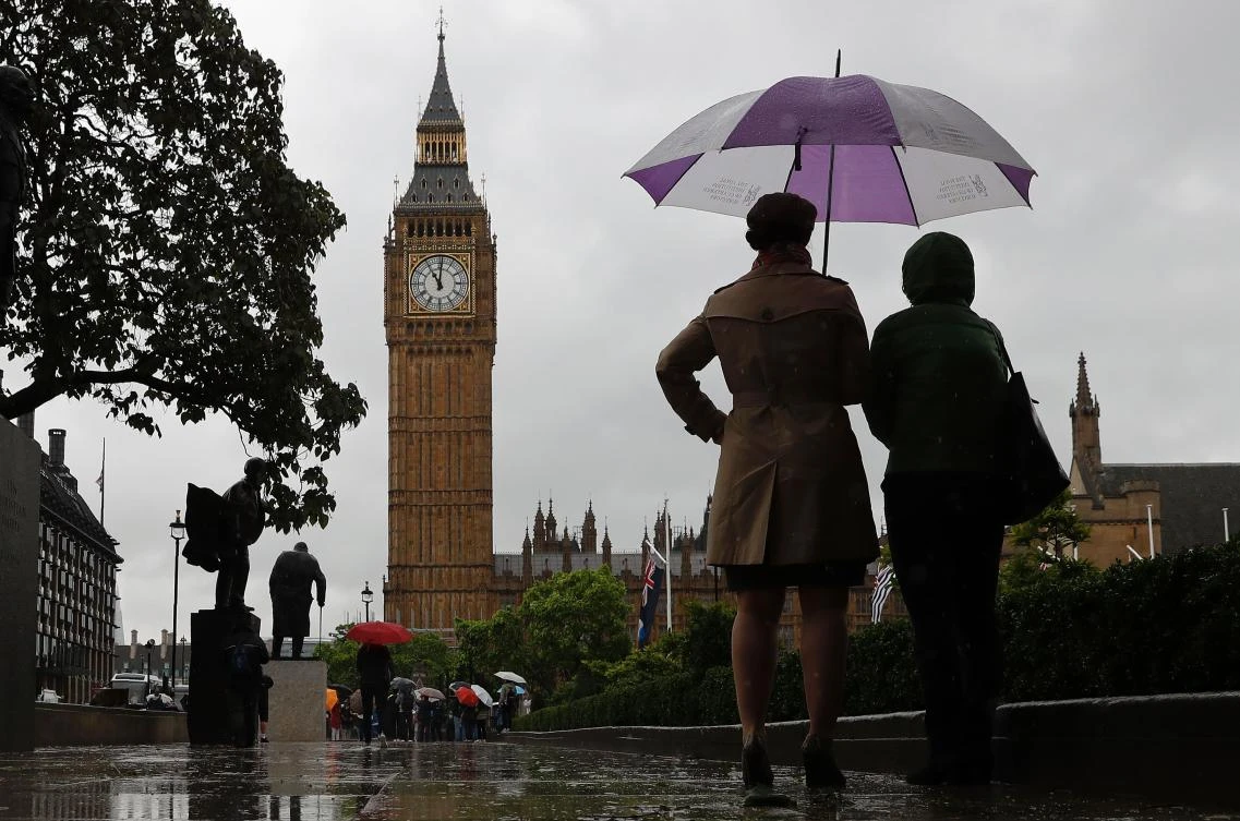 People shelter from the rain beneath an umbrella as they observe a minutes’ silence near the Elizabeth Tower, commonly referred to as Big Ben, at the Houses of Parliament in London on June 6, 2017, in memory of the victims of the June 3 terror attacks. (AFP)