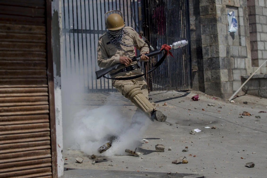 An Indian policeman kicks an exploded tear gas shell in an attempt to thrown it at Kashmiri protesters in Srinagar on Friday. (AP)