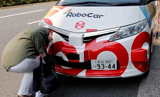 A woman looks at ZMP Inc's RoboCar MiniVan, a self-driving Toyota Estima Hybrid car, after a joint news conference between ZMP and Hinomaru Kotsu Co in Tokyo, Japan on Thursday. (REUTERS)