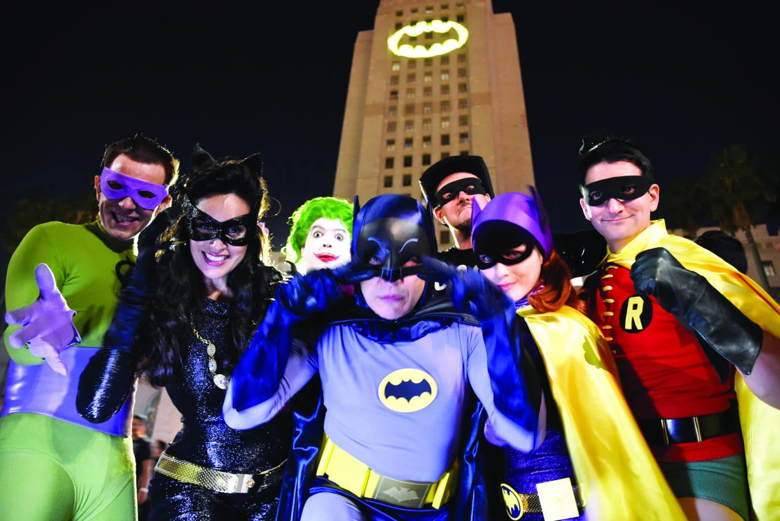 Fans dressed as fictional characters pose in front of a Bat-signal projected onto City Hall in Los Angeles on Thursday. (AP)