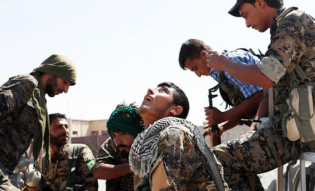 A Kurdish fighter from the People's Protection Units (YPG) reacts on a sound of a drone operated by Daesh militants in Raqqa, Syria on Friday. (REUTERS)