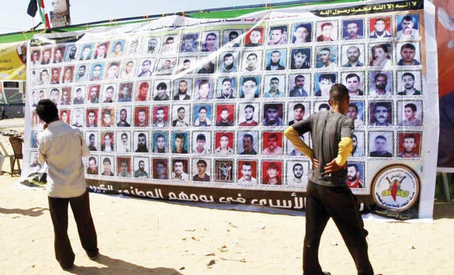 Palestinians stand in front of a big banner showing portraits of Palestinians held in Israeli jails in this file photo. (AFP)