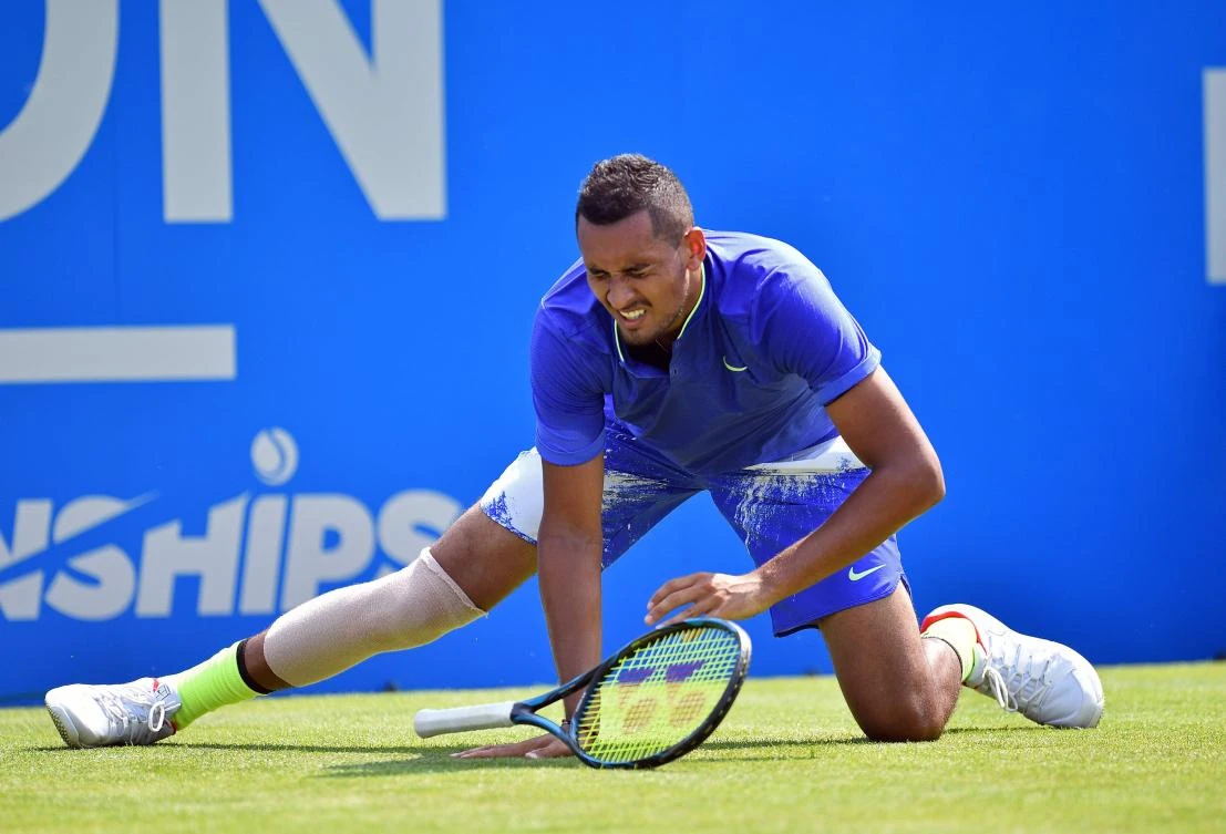 Australia's Nick Kyrgios slips and is forced to retire in a fresh injury blow ahead of Wimbledon during his men's singles first round match against Donald Young of the US at the ATP Aegon Championships tennis tournament at Queen's Club in west London on Monday. (AFP)