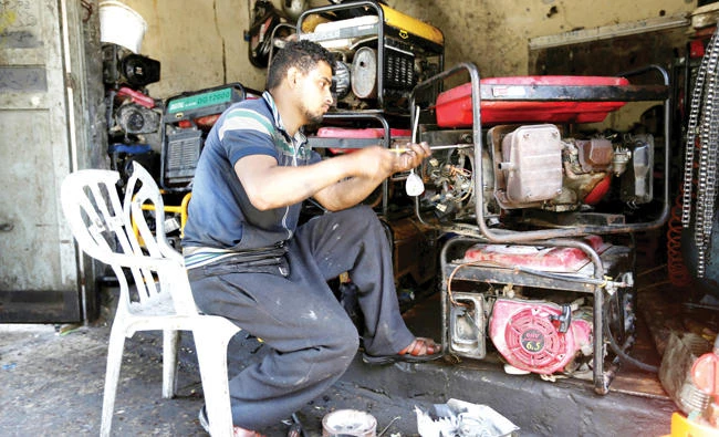 A Palestinian man repairs generators at his shop in Khan Younis, Gaza Strip. (Reuters)
