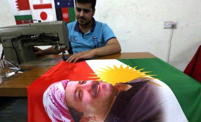 An Iraqi man sews a flag of Kurdistan bearing the portrait of Iraqi Kurdish leader Massud Barzani, in Irbil, the capital of the autonomous Kurdish region of northern Iraq, on June 8, 2017.(AFP / SAFIN HAMED)