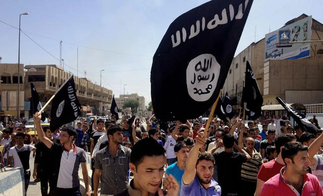 In this June 16, 2014 file photo, young Iraqis rally behind the Daesh group in front of the provincial government headquarters in Mosul, Iraq. A Canadian citizen of Afghan origin was convicted on Monday of violating a law banning people from trying to leave Canada to join the Daesh in Syria to commit a terrorist act. (AP Photo, File)