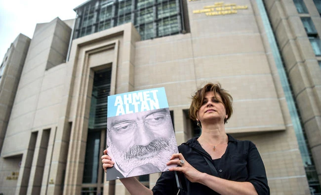 A journalist poses with a portrait of Turkish journalist Ahmet Altan in front of the Istanbul courthouse, where his trial is to take place. 17 suspects, including jailed journalists Nazli Ilicak, Ahmet Altan and Mehmet Altan, will appear before an Istanbul court on Monday. (AFP)