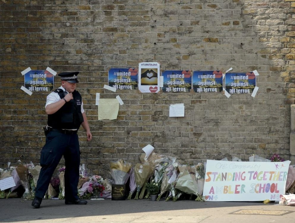 A policeman stands near floral tributes left after an incident, close to Finsbury Park Tube Station, in north London, Monday, June 19, 2017. (AP)