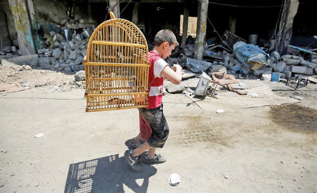 An Iraqi boy carries a birdcage as he flees from the Old City of Mosul Tuesday. (AFP)