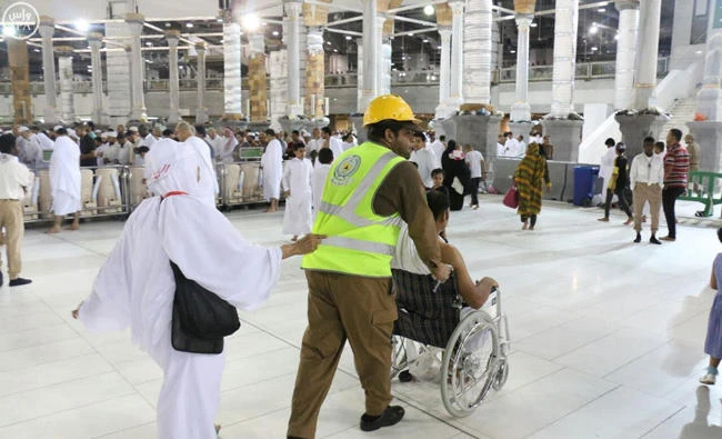 A Civil Defense member assists a pilgrim on his way to perform Umrah rituals at the Grand Mosque in Makkah. (SPA file photo)