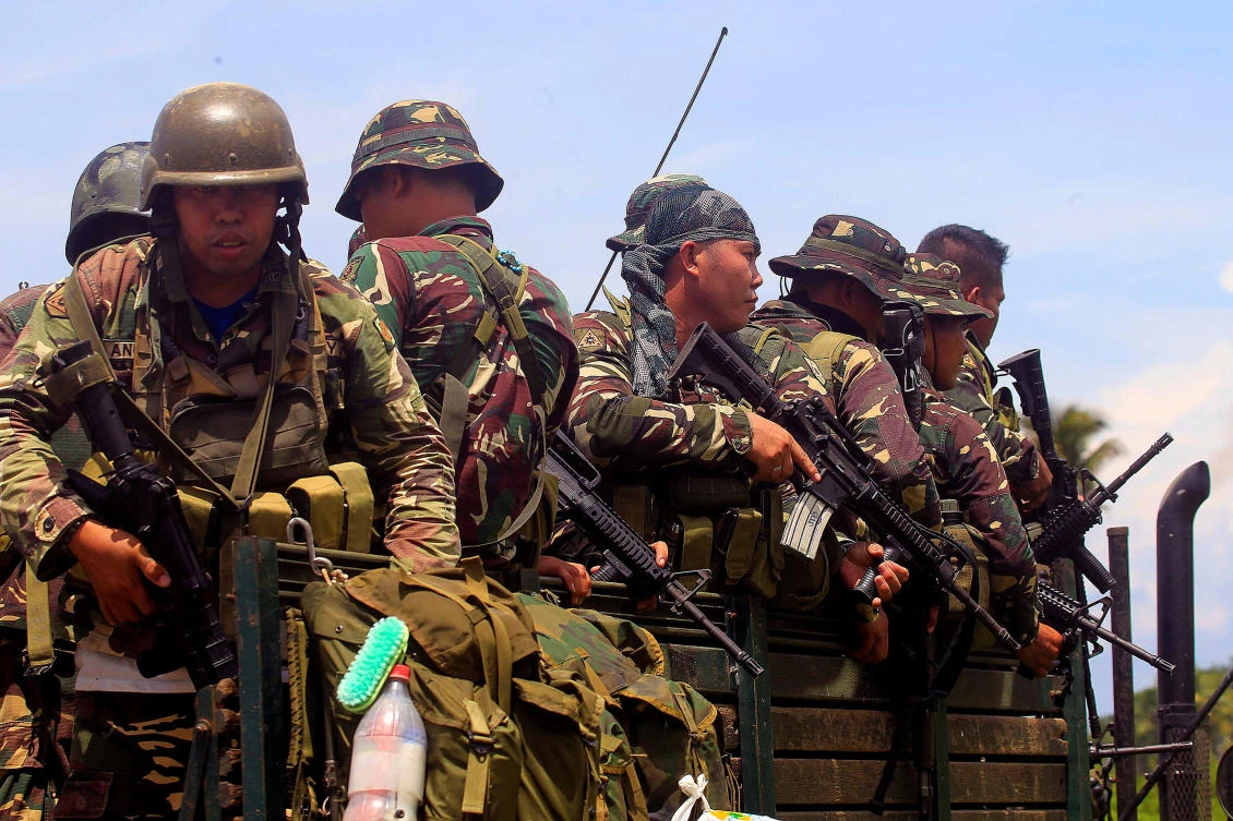 Government forces board a military truck after militants, who had holed up in a primary school, retreated after a gun battle with troops but were holding some civilians hostage, in Pigcawayan, North Cotabato, on Wednesday. (Reuters)