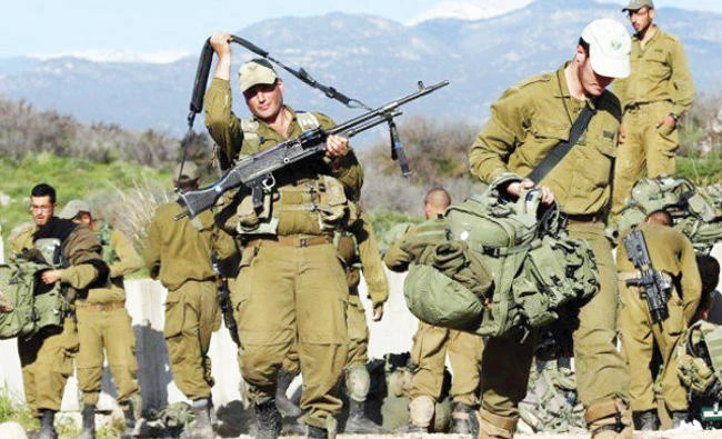 Israeli soldiers carry their belongings in an area near the Israel-Lebanon border in this file photo. (Reuters)