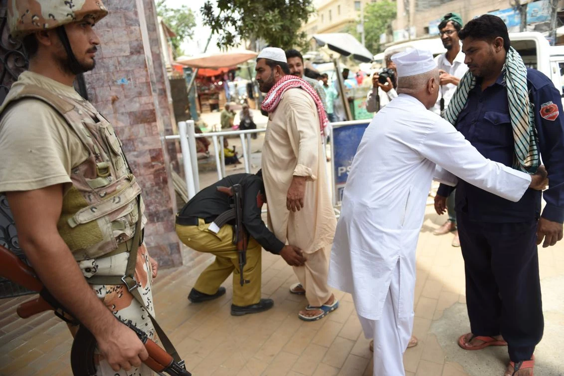 Pakistani security personnel search worshipers before entering a mosque in Karachi on Friday. (AFP)