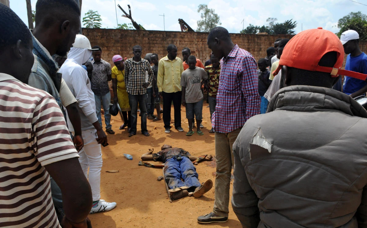 Civilians gather to look at the dead body of an unidentified man killed during fighting between the army and militia in the DRC. (Reuters)