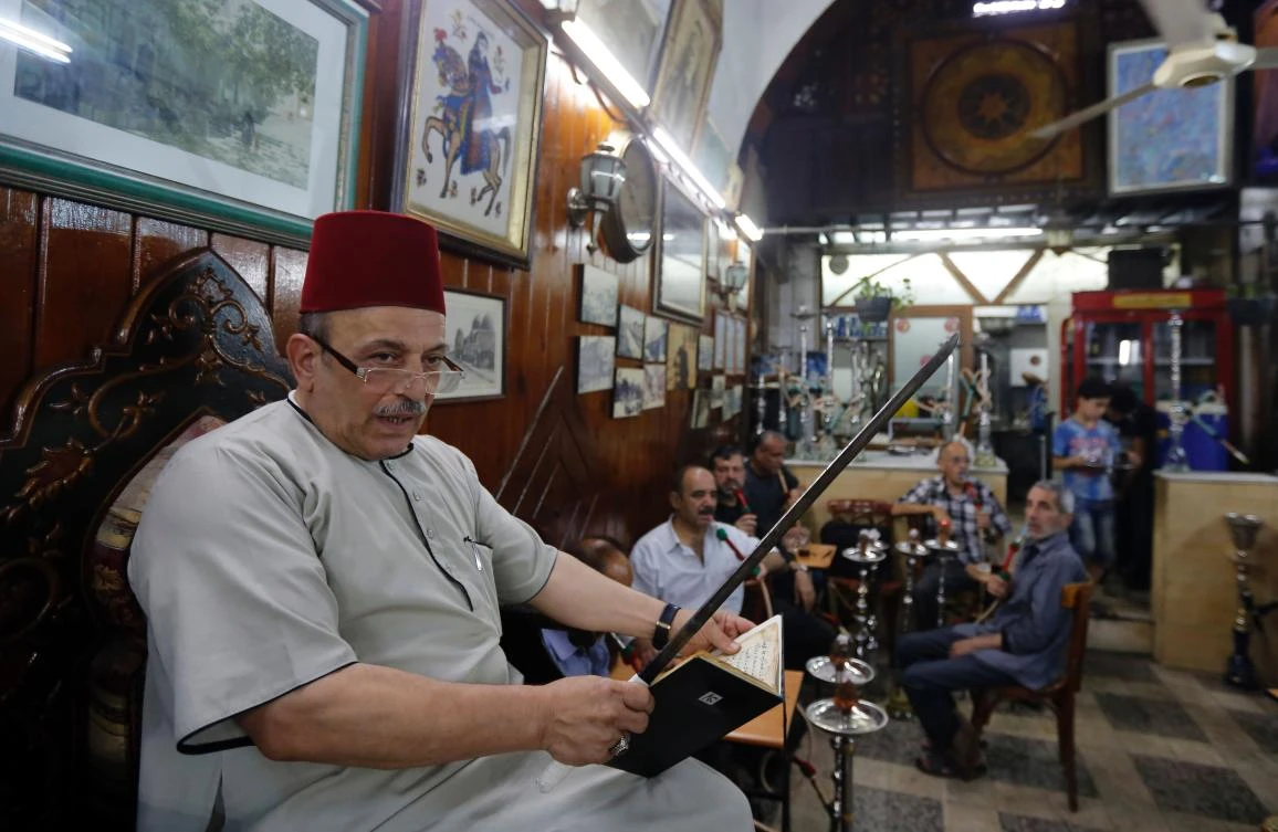 Ahmad Al-Lahham, a Syrian storyteller, reads from his storybook in a Damascus coffeehouse on Monday. (AFP)