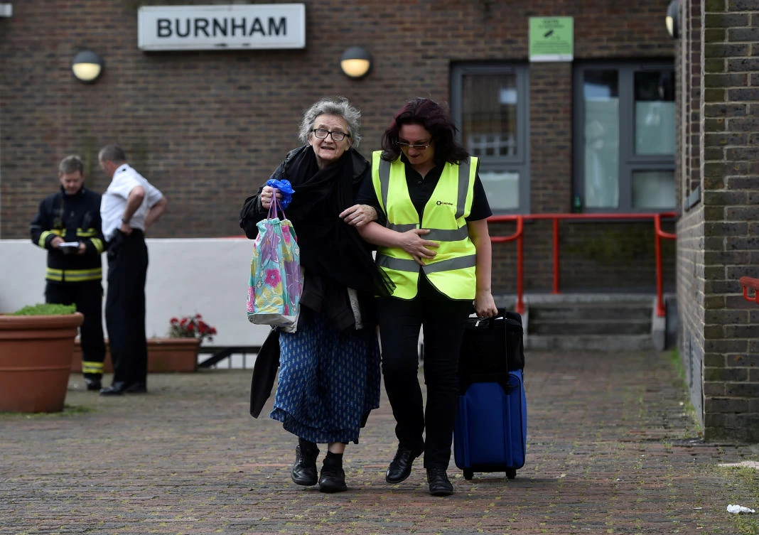 A resident is evacuated from the Burnham Tower residential block in London on Saturday. (Reuters)