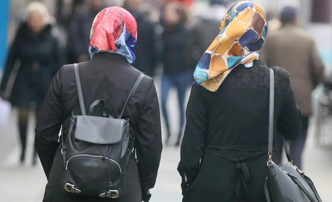 In this April 21, 2017 photo women with head scarfs are walking in a pedestrian zone in Vienna. Austria is now cracking down on naturalized citizens from Turkey who continue to hold on to their citizenship. (AP Photo/Ronald Zak,file)