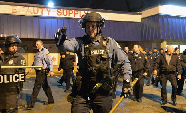 In this December 24, 2014 photo, police officers in Berkeley, Missouri attempt to disperse demonstrators protesting the shooting of a black teenager after he allegedly pointed a gun at an officer. On Saturday, a police officer in St. Louis County, Missouri, shot a black off-duty cop who was trying to assist fellow officers during a firefight with crime suspects. (AFP file photo)
