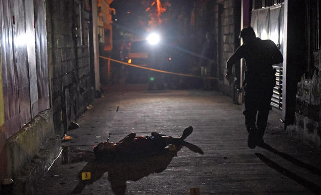 A body lies on the ground as police investigators examine a crime scene of a drug-related shooting by unidentified masked men at Navotas city in metropolitan Manila, Philippines, on June 19, 2017. (REUTERS/Dondi Tawatao)