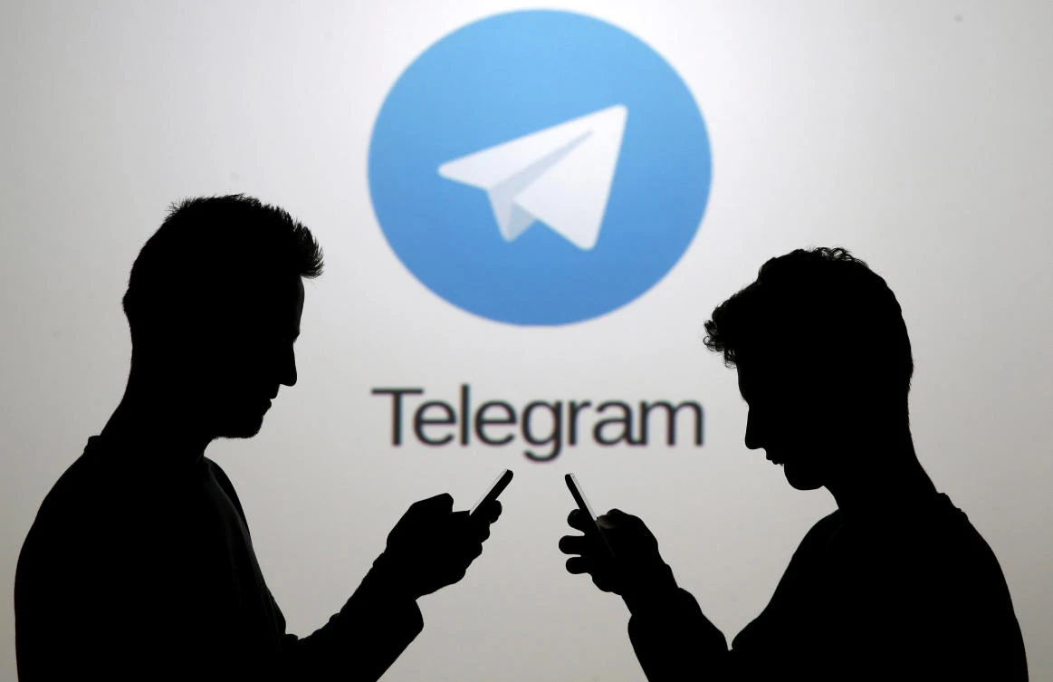 FILE PHOTO: Men pose with smartphones in front of a screen showing the Telegram logo in this picture illustration. (REUTERS)