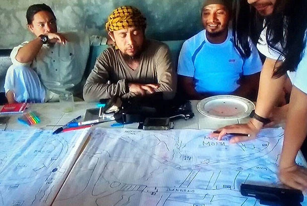 This image taken from undated video shows the purported leader of the Daesh group Southeast Asia branch, Isnilon Hapilon, center, at a meeting of militants at an undisclosed location. The images offer a rare glimpse into the clandestine operations of insurgents who followed through two weeks ago with an unprecedented assault on the lakeside city of Marawi, parts of which they still occupy today. (AP)