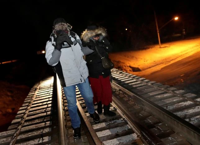 FILE PHOTO - Refugees walk along railway tracks from the United States to enter Canada at Emerson, Manitoba, Canada, on February 26, 2017. (REUTERS)