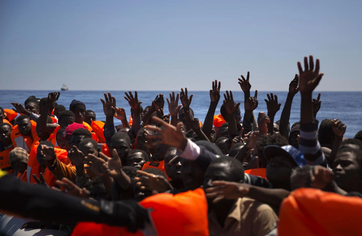 Migrants and refugees raise their hands as they try to reach life vests, after being located out of control sailing on a rubber boat in the Mediterranean Sea, about 18 miles north of Sabratha, Libya in this June 15 photo. (AP)