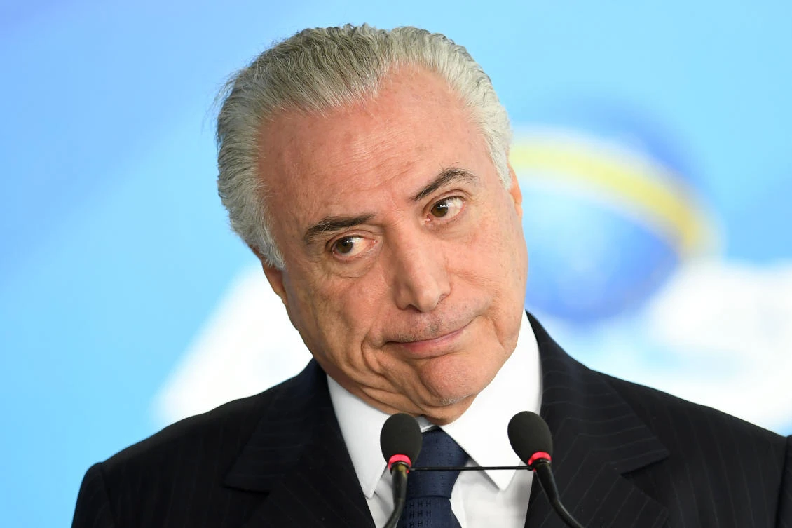 Brazilian President Michel Temer gestures during the signing ceremony of the decree that frees differential prices for payment in cash and with credit card at the Planalto Palace in Brasilia, on June 26, 2017. Temer faces his own crisis with the prosecutor general expected to request formal corruption charges against the president. (AFP / EVARISTO SA)