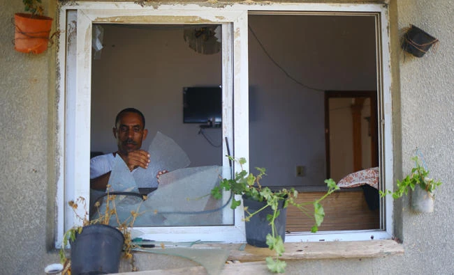 A Palestinian man removes broken glass from his window following an Israeli air strike in Gaza City on Tuesday. (AFP / MOHAMMED ABED)