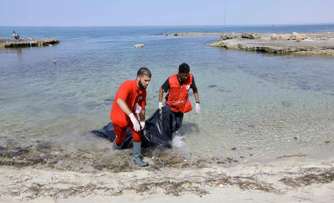 Rescuers carry a bag containing the dead body of a migrant at the coast of Tajoura, east of Tripoli, Libya, on June 27, 2017. (REUTERS/Ismail Zitouny)