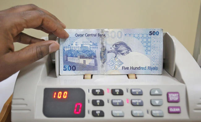 A cashier counts Qatari notes at a money changer in Doha. (Reuters file photo)