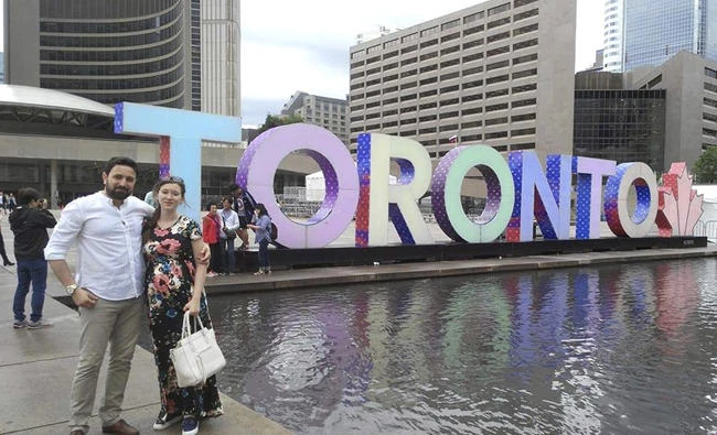 In this June 26, 2017 photo, Khaled Almilaji poses with his wife, Jehan, in Toronto. Dr. Almilaji, who coordinated a campaign that vaccinated 1.4 million Syrian children and risked his life to provide medical care during the country's civil war, says he won't return to the US to finish his studies at Brown University because of the Trump administration's travel ban. (Courtesy of Khaled Almilaji via AP)