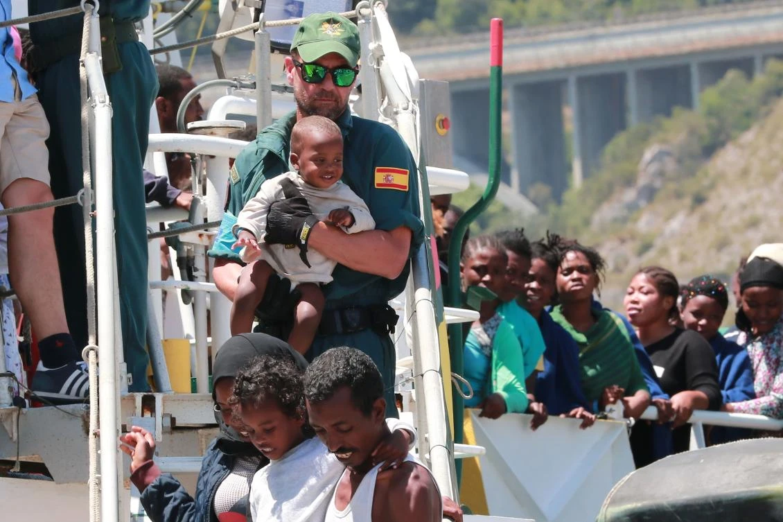 A Guardia Civil officers helps migrants to disembark from the Spanish Guardia Civil Rio Segura Patrol Ship with 1,216 migrants onboard including 256 children and 11 pregnant women, who were rescued in the Mediterranean sea on June 29, 2017, in the port of Salerno. (AFP)