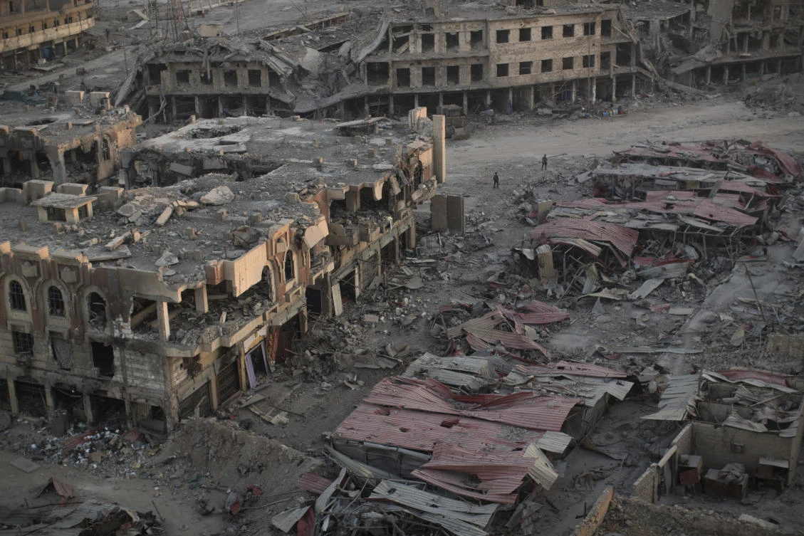 In this July 11, 2017 photo, people walk through a damaged neighborhood as the sun sets on the west side of Mosul, Iraq. Iraq’s U.S.-backed forces succeeded in wresting Mosul from the Islamic State group but at the cost of enormous destruction. The nearly 9-month fight culminated in a crescendo of devastation _ the blasting of the historic Old City to root out the militants’ final pockets. (AP)
