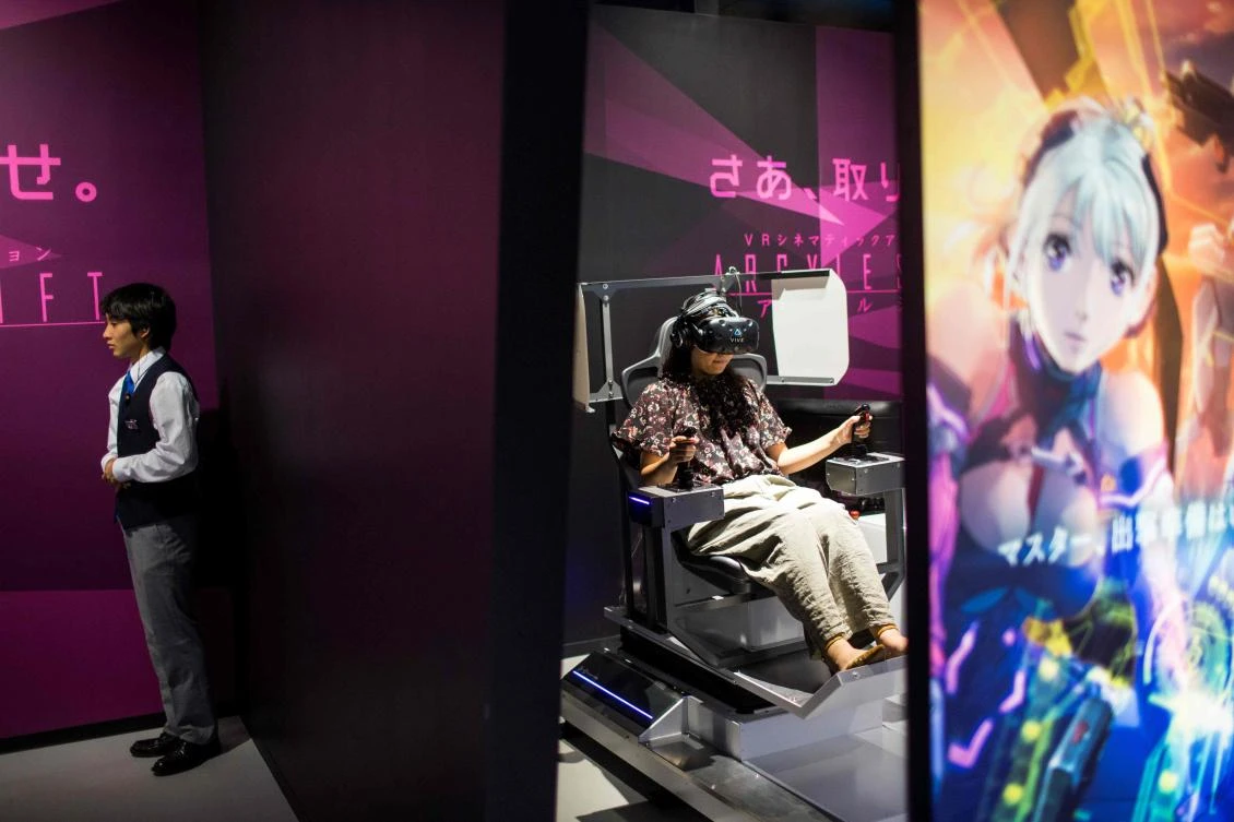 A woman (C) plays a virtual reality (VR) game at the Bandai Namco game facility of VR Zone Shinjuku in Tokyo on July 22, 2017. / AFP / Behrouz MEHRI