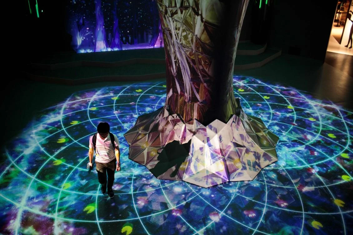 A man walks next to a projection mapping touch reactive installation at the Bandai Namco game facility of VR Zone Shinjuku in Tokyo on July 22, 2017. / AFP / Behrouz MEHRI
