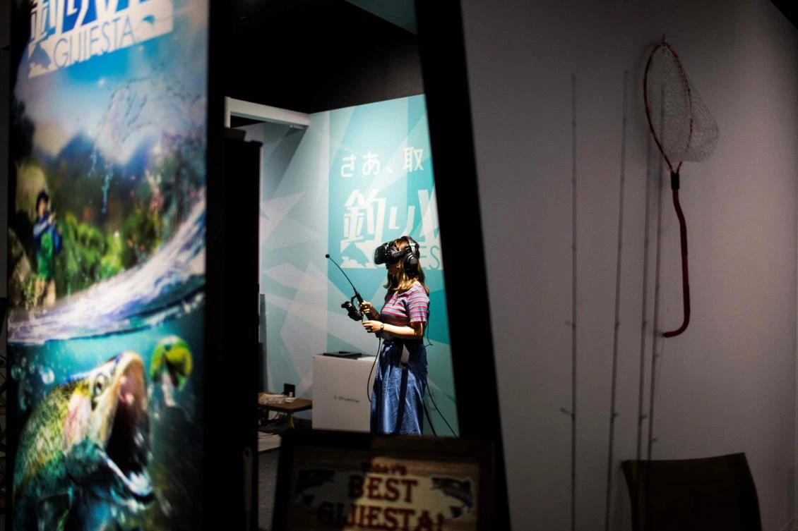 A woman plays a virtual reality (VR) fishing game at the Bandai Namco game facility of VR Zone Shinjuku in Tokyo on July 22, 2017. / AFP / Behrouz MEHRI