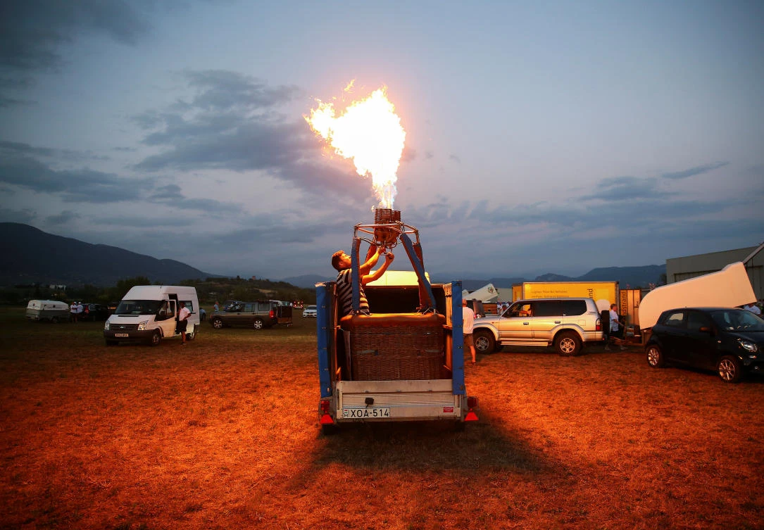 A man fires up his hot air balloon while standing in the basket during an Italian hot air ballooning event in Terni, Italy, July 28, 2017. REUTERS/Alessandro Bianchi