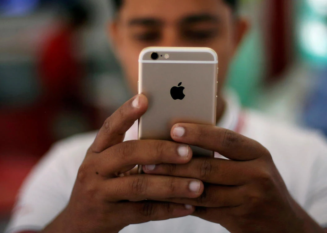 A salesman checks a customer's iPhone at a mobile phone store in New Delhi, India. Shoppers were vacuuming up household gadgets and high-end electronics in many New Delhi stores on Friday in the last days before India’s new sales tax takes effect. (REUTERS/Adnan Abidi/File photo)