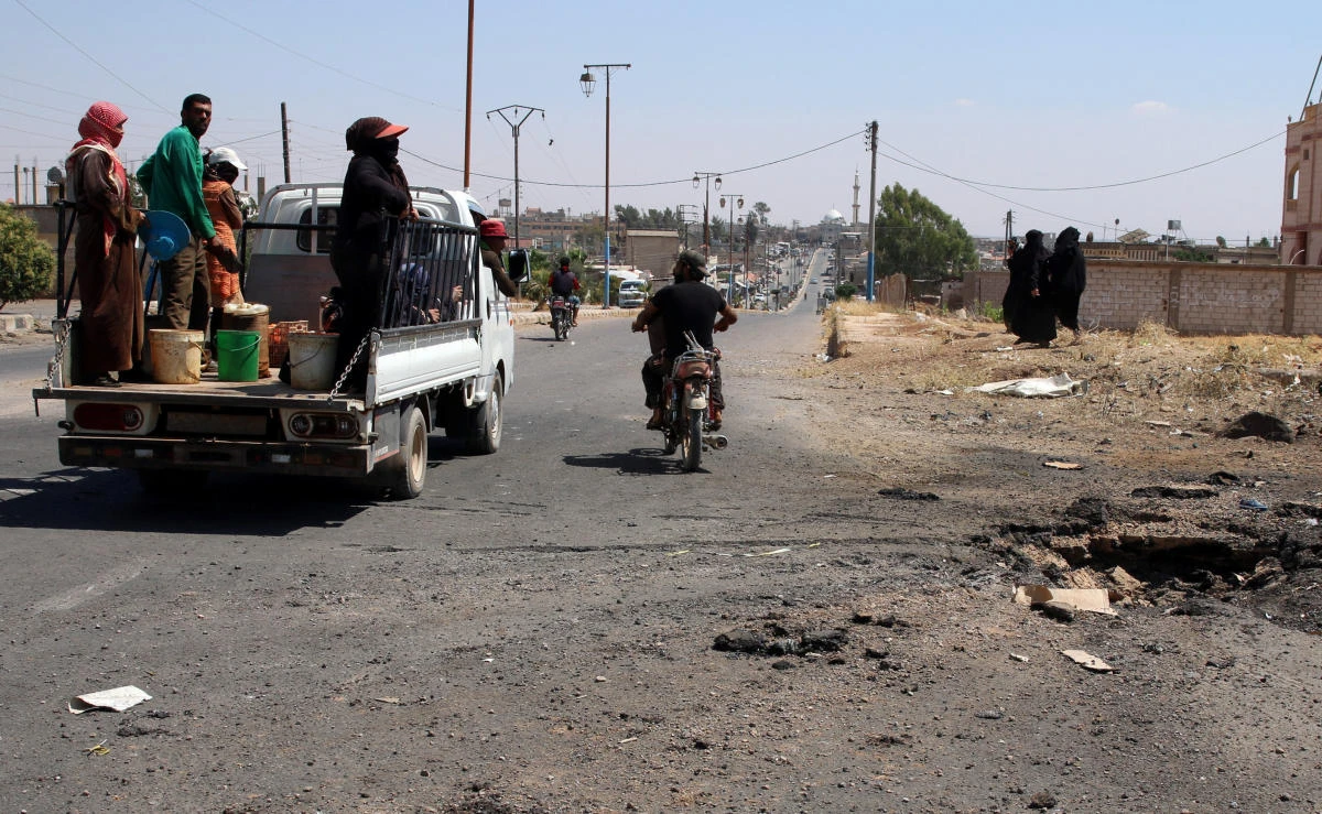 People ride on a pick-up truck near a site hit by an airstrike in the rebel-held town of Muzayrib, in Deraa province on Saturday. (Reuters)