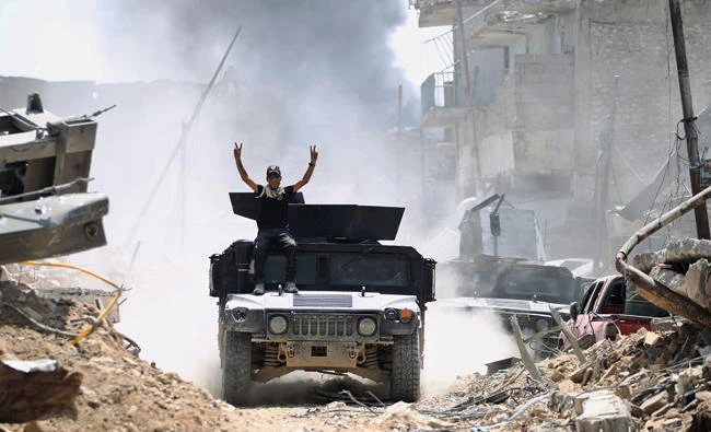 A member of the Iraqi Counter-terrorism Service (CTS), sitting atop an advancing humvee, shows the victory sign in the Old City of Mosul. (AFP)