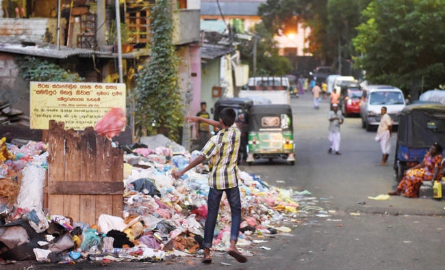 A man throws trash onto garbage piled on a street in Colombo in this June 26 file photo. (AFP)