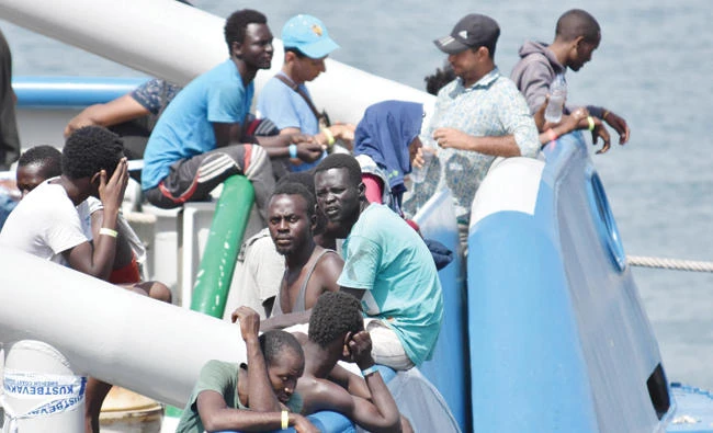 Migrants stand on the deck of the Swedish Navy ship Bkv 002, as they wait to disembark in the Sicilian harbor of Catania, Italy, on Saturday. (AP)