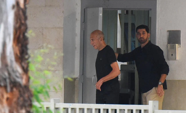 Former Israeli Prime Minister Ehud Olmert walks out of the prison door as he is released from prison after a parole board decided to cut his sentence by a third, at Maasiyahu prison near Ramle, Israel on Sunday. (Reuters)