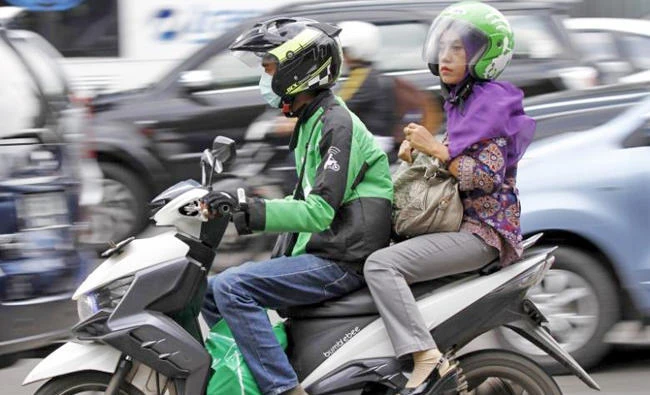 A woman rides on the back of a motorbike, part of the Go-Jek ride-hailing service, on a busy street in central Jakarta, Indonesia. (REUTERS file photo)