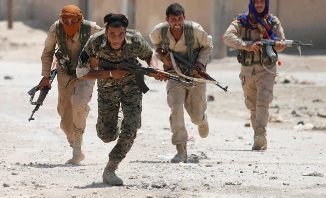Kurdish fighters from the People's Protection Units (YPG) run across a street in Raqqa, Syria on July 3, 2017. (REUTERS/Goran Tomasevic)